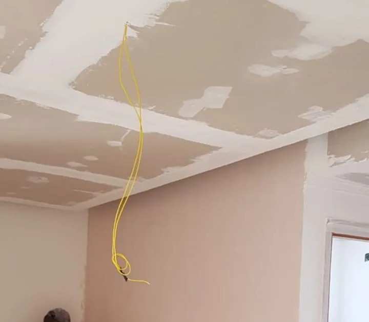 Ambiente durante a obra, com teto em gesso e parede preparada