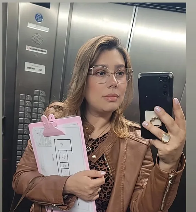 Karina no elevador com a prancheta do projeto, começando o dia de obra